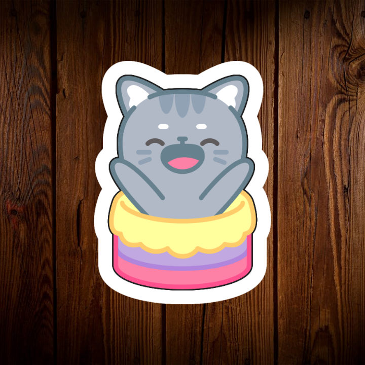 Trong hình ảnh, chúng ta thấy một chú mèo xám nhỏ đang nằm gọn trong một chiếc bánh kem nhiều tầng đầy màu sắc. Chú mèo đang cười rất tươi, đôi mắt tròn xoe, miệng há rộng để lộ hàm răng trắng sáng. Toàn bộ cơ thể chú mèo như đang đắm chìm trong niềm vui sướng. Chiếc bánh kem phía dưới có nhiều lớp màu sắc pastel ngọt ngào, tạo nên một khung cảnh vô cùng bắt mắt và hấp dẫn.